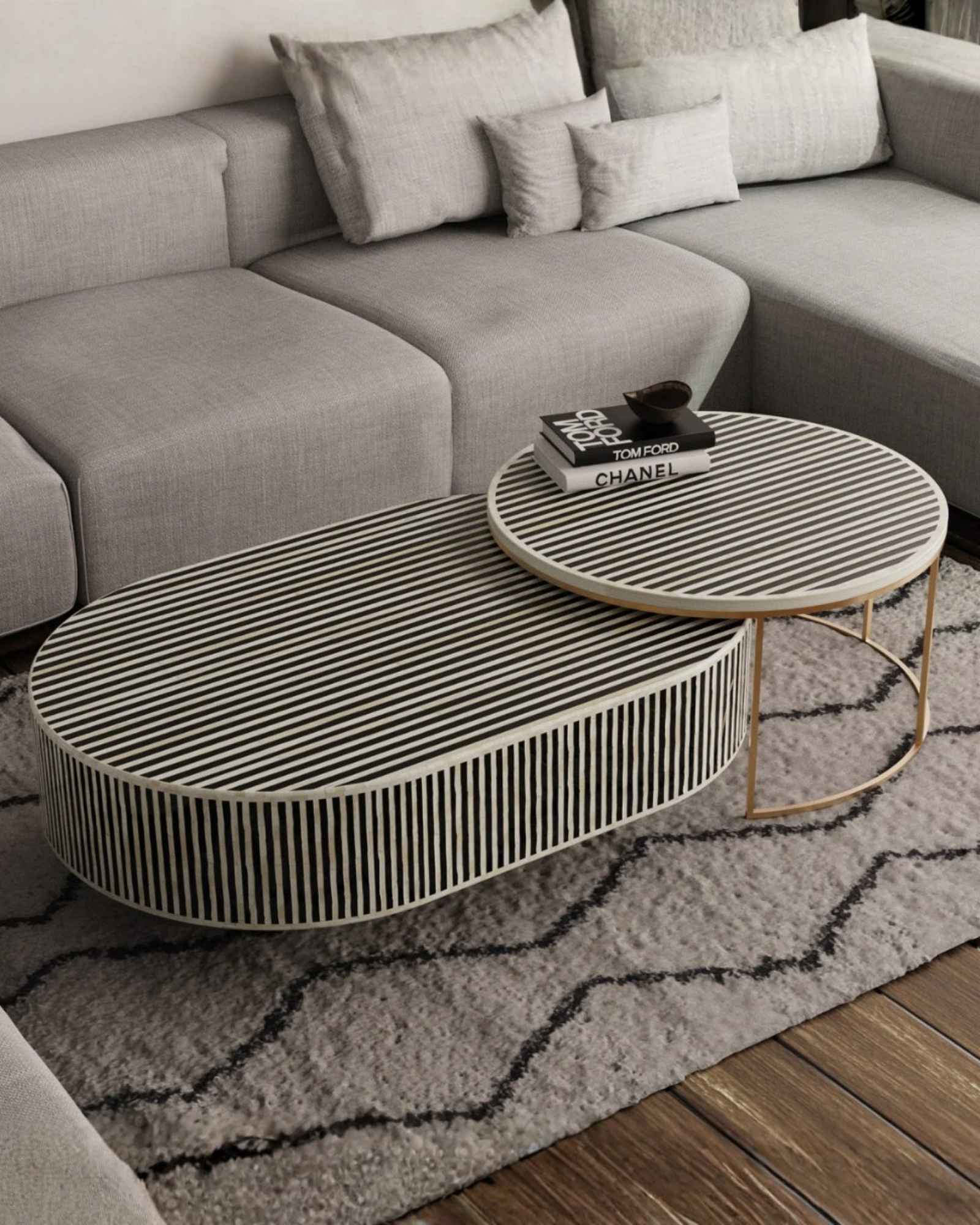 Black bone inlay nesting coffee table with vertical striped pattern and gold base, styled in a modern living room.
