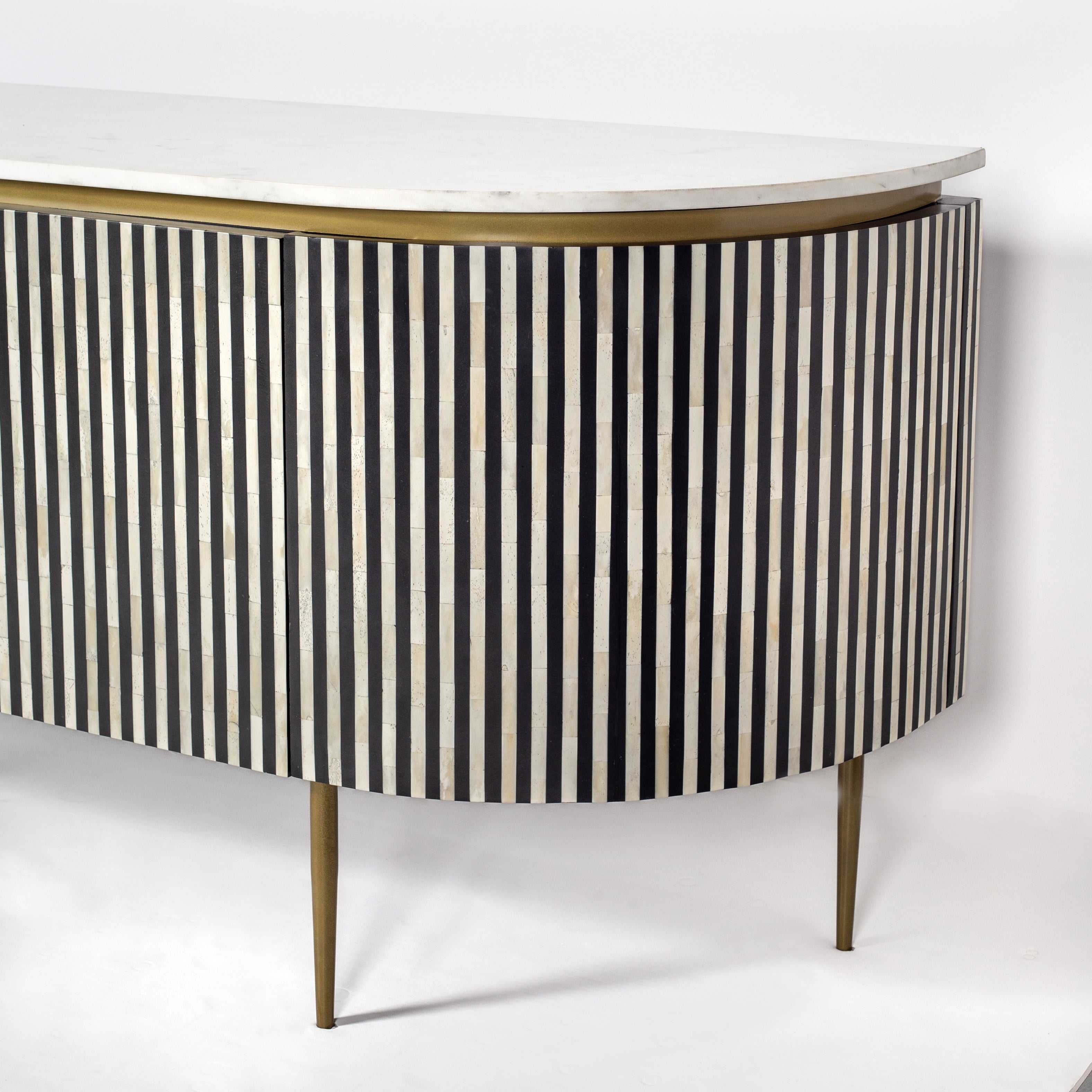Black bone inlay sideboard with white marble top and brass legs, handcrafted with vertical striping and curved silhouette, luxury interior furniture.