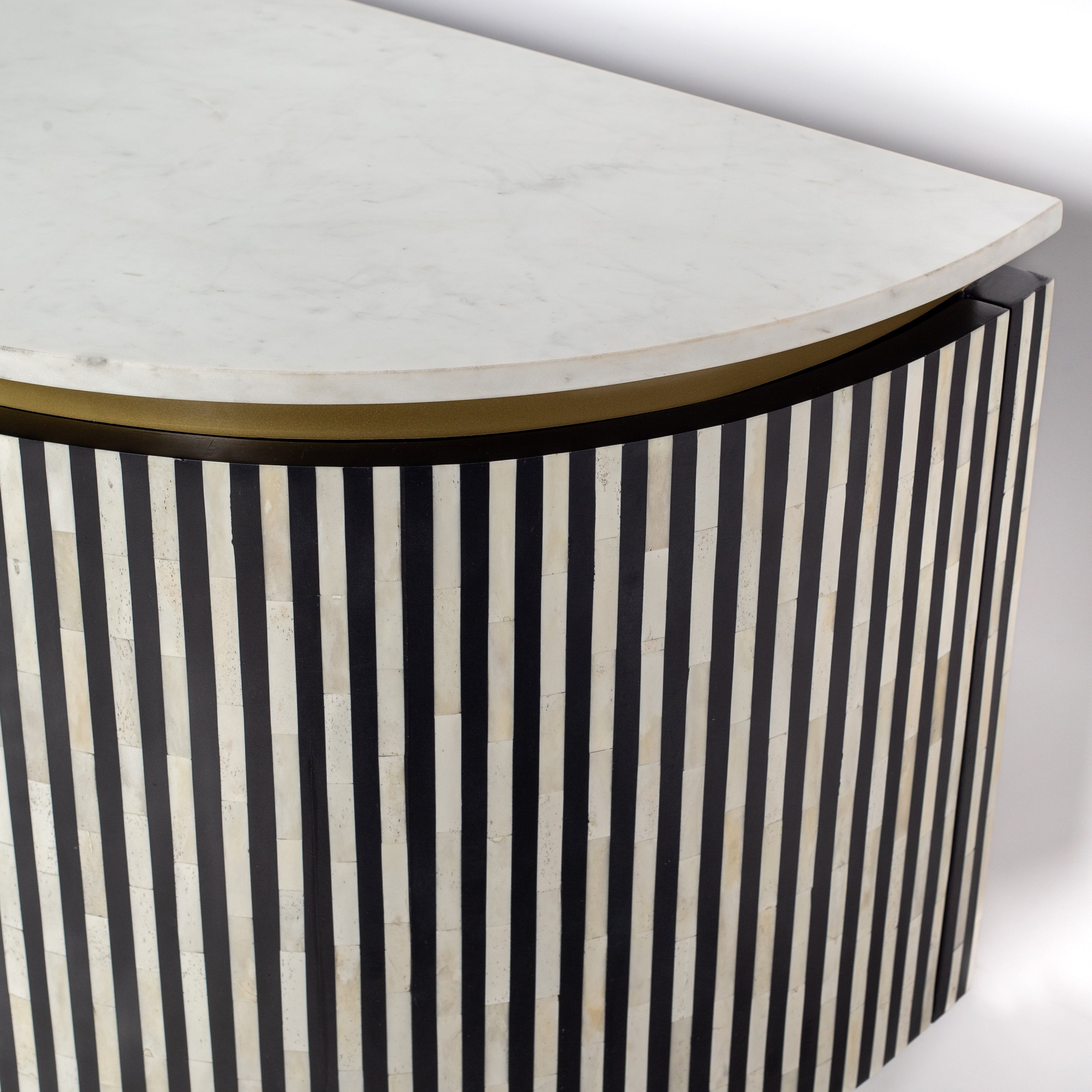 Black bone inlay sideboard with white marble top and brass legs, handcrafted with vertical striping and curved silhouette, luxury interior furniture.