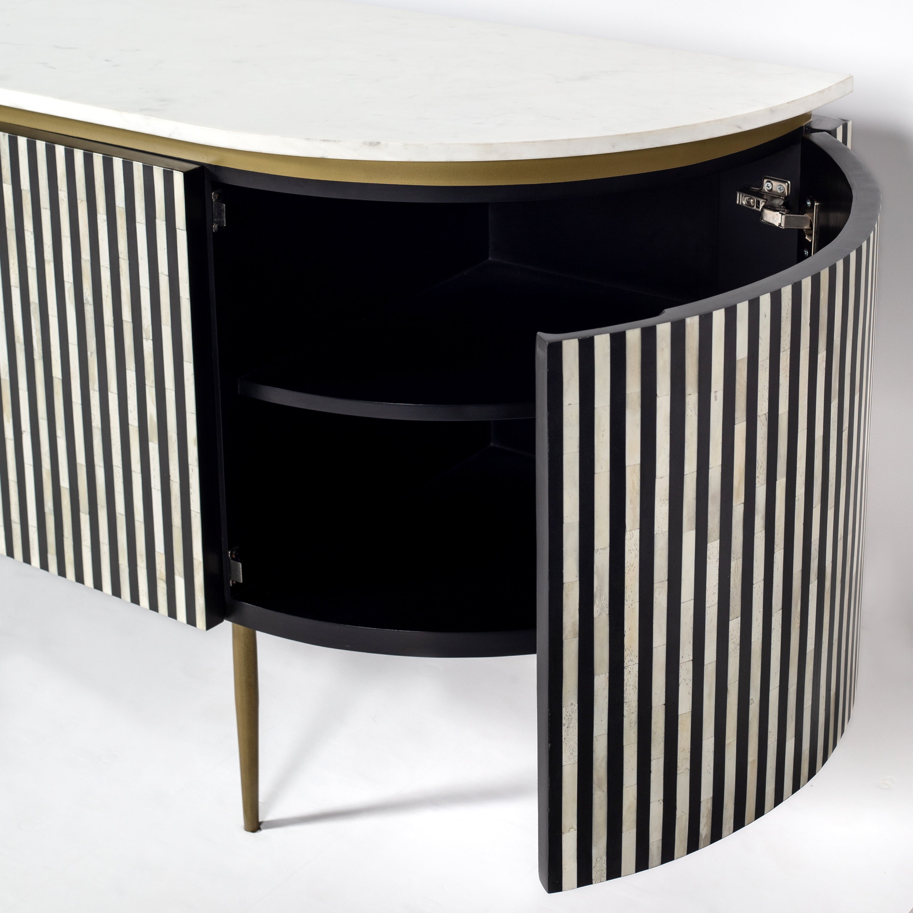 Black bone inlay sideboard with white marble top and brass legs, handcrafted with vertical striping and curved silhouette, luxury interior furniture.
