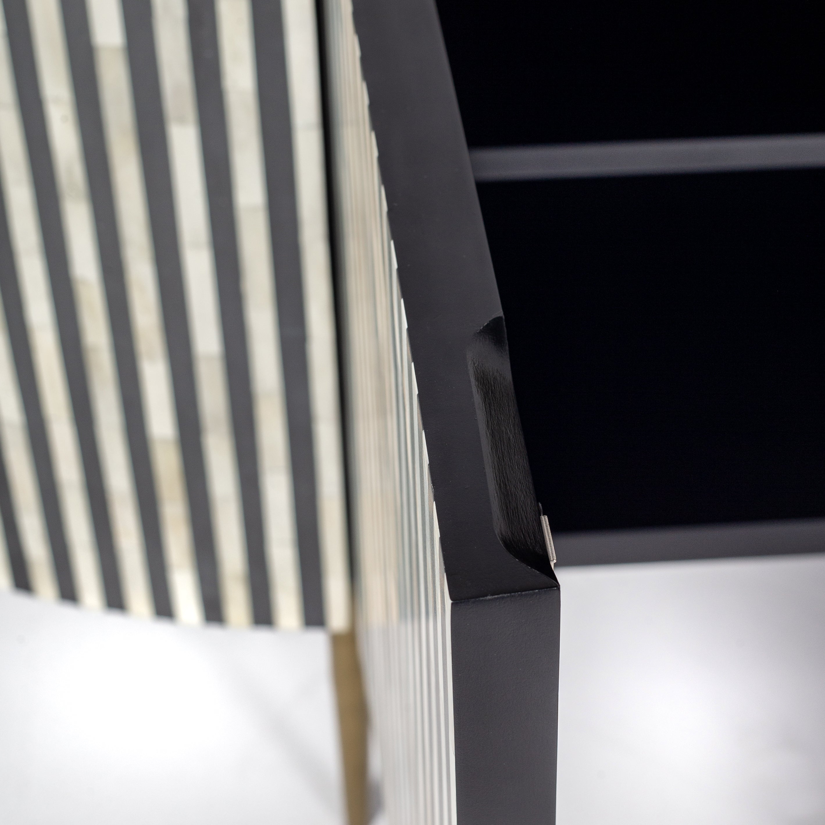 Black bone inlay sideboard with white marble top and brass legs, handcrafted with vertical striping and curved silhouette, luxury interior furniture.
