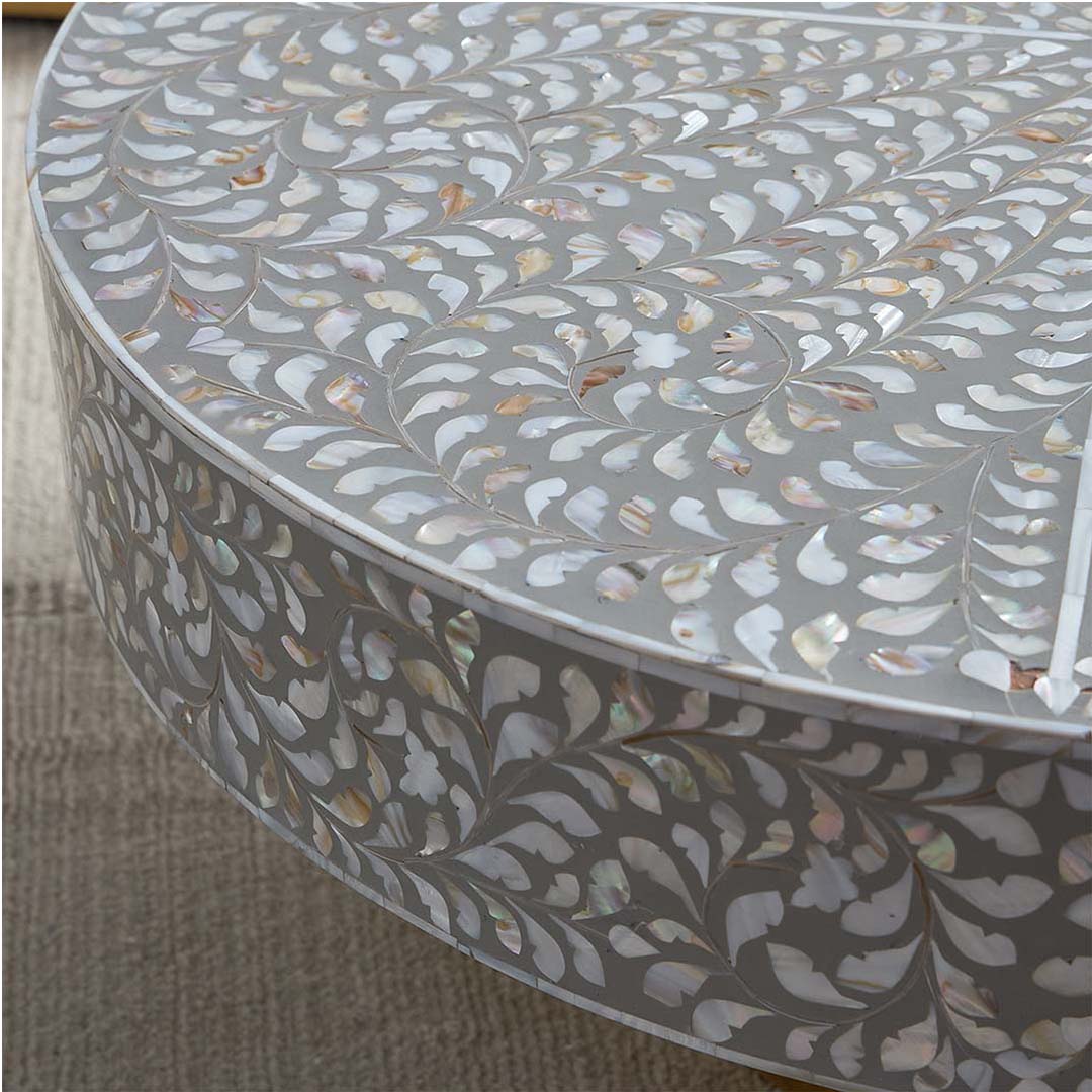 Round grey mother of pearl inlay coffee table with intricate floral design and a gold cylindrical metallic base.