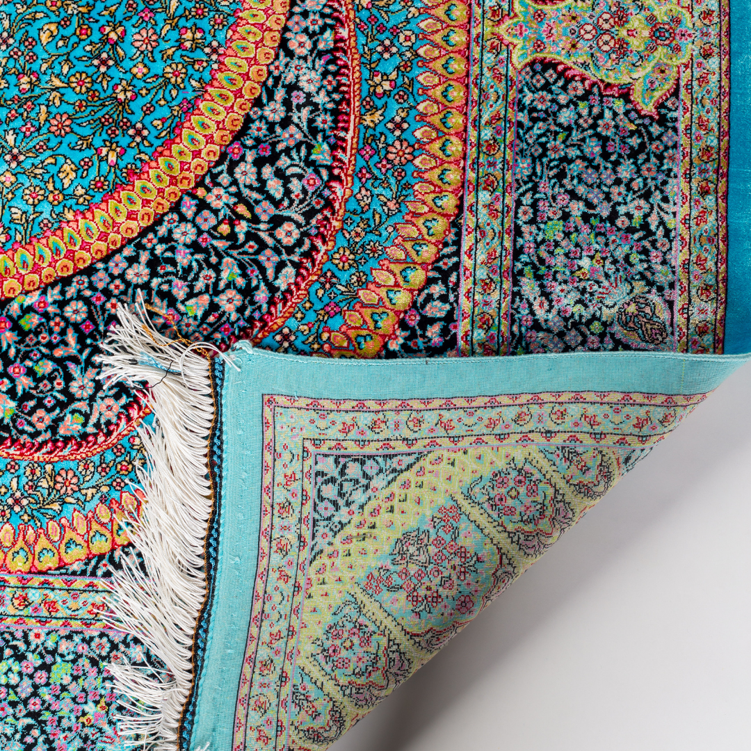 Vortex Silk Rug featuring a central floral medallion on a turquoise base with red, green, and black detailing, size 150x100 cm.