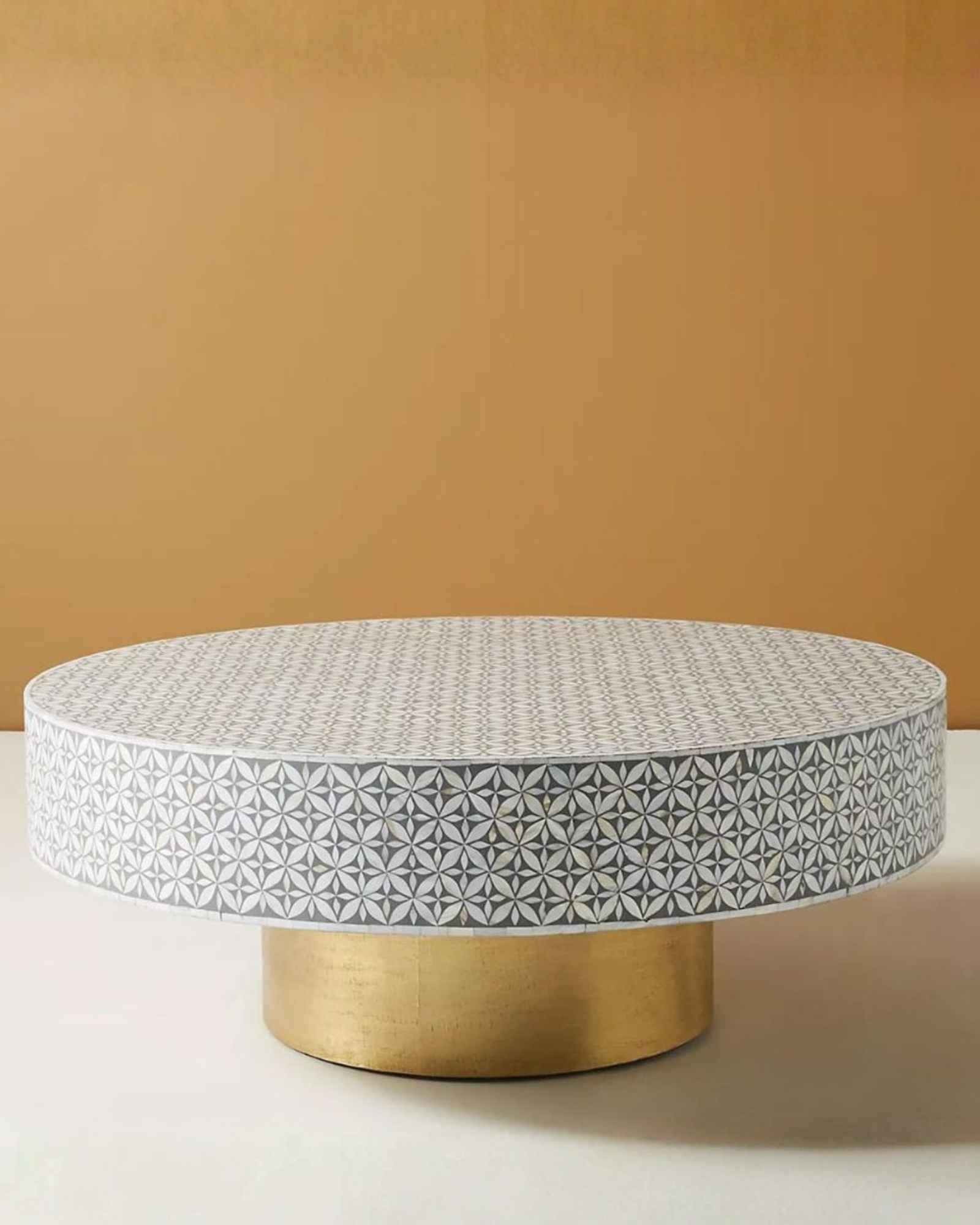 Round grey bone inlay coffee table with floral design and a bold gold base. A stylish and modern centerpiece for any living room.