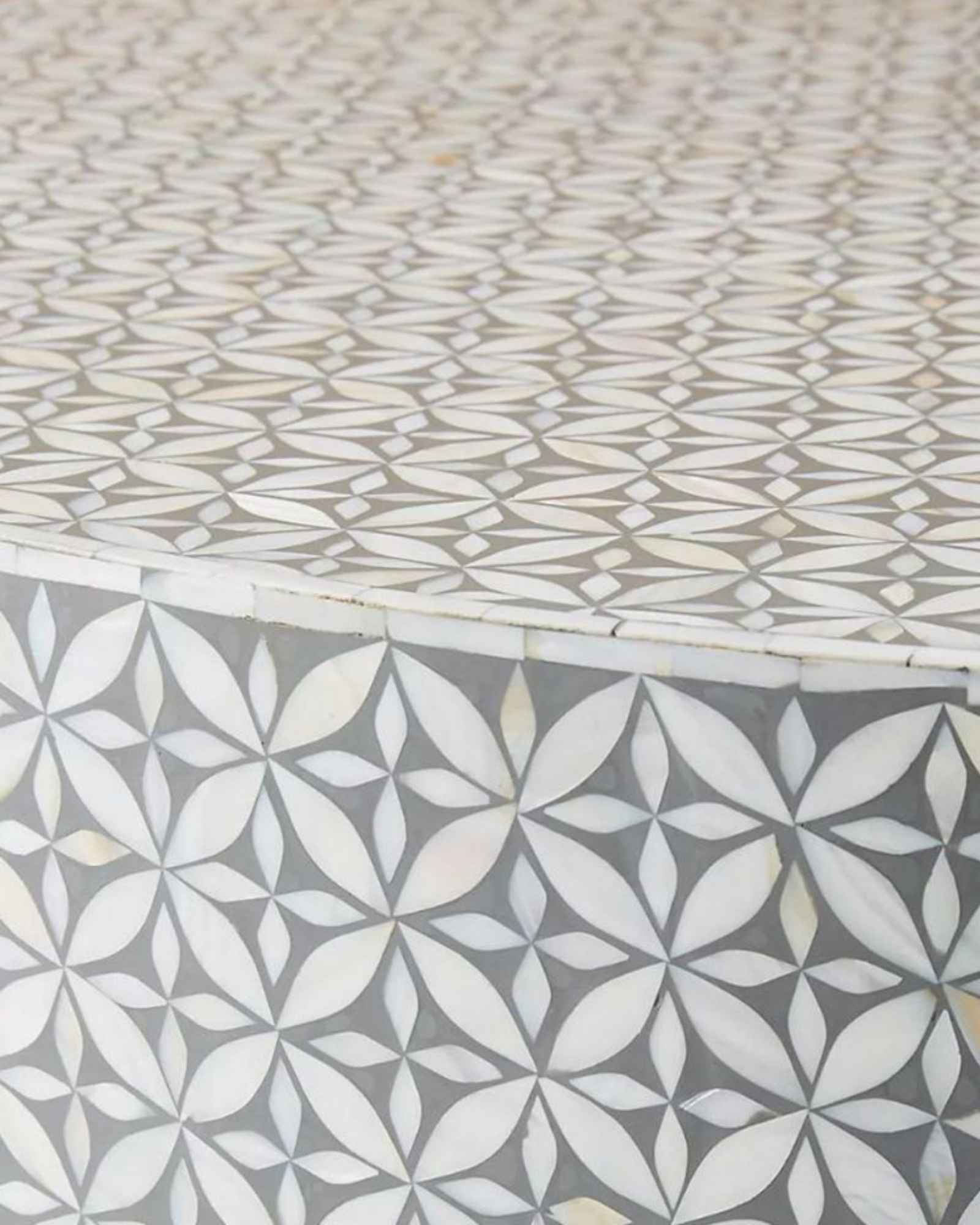 Round grey bone inlay coffee table with floral design and a bold gold base. A stylish and modern centerpiece for any living room.