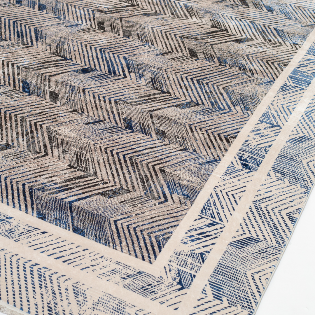 Zira cotton rug featuring a bold chevron pattern in grey, blue, and ivory with a distressed texture, perfect for contemporary interiors.
