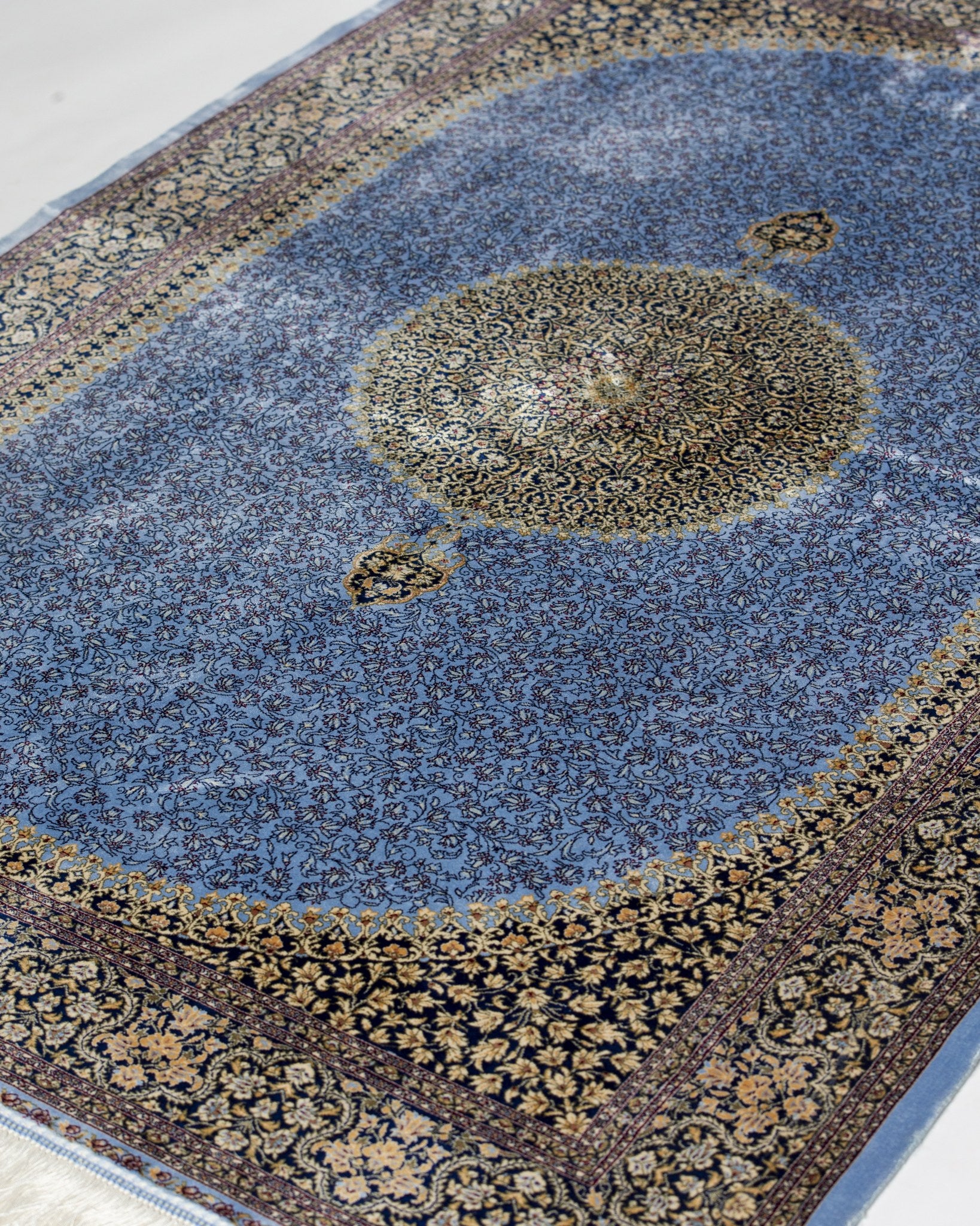 Full view of the Aseman silk rug medallion in gold and ivory on blue