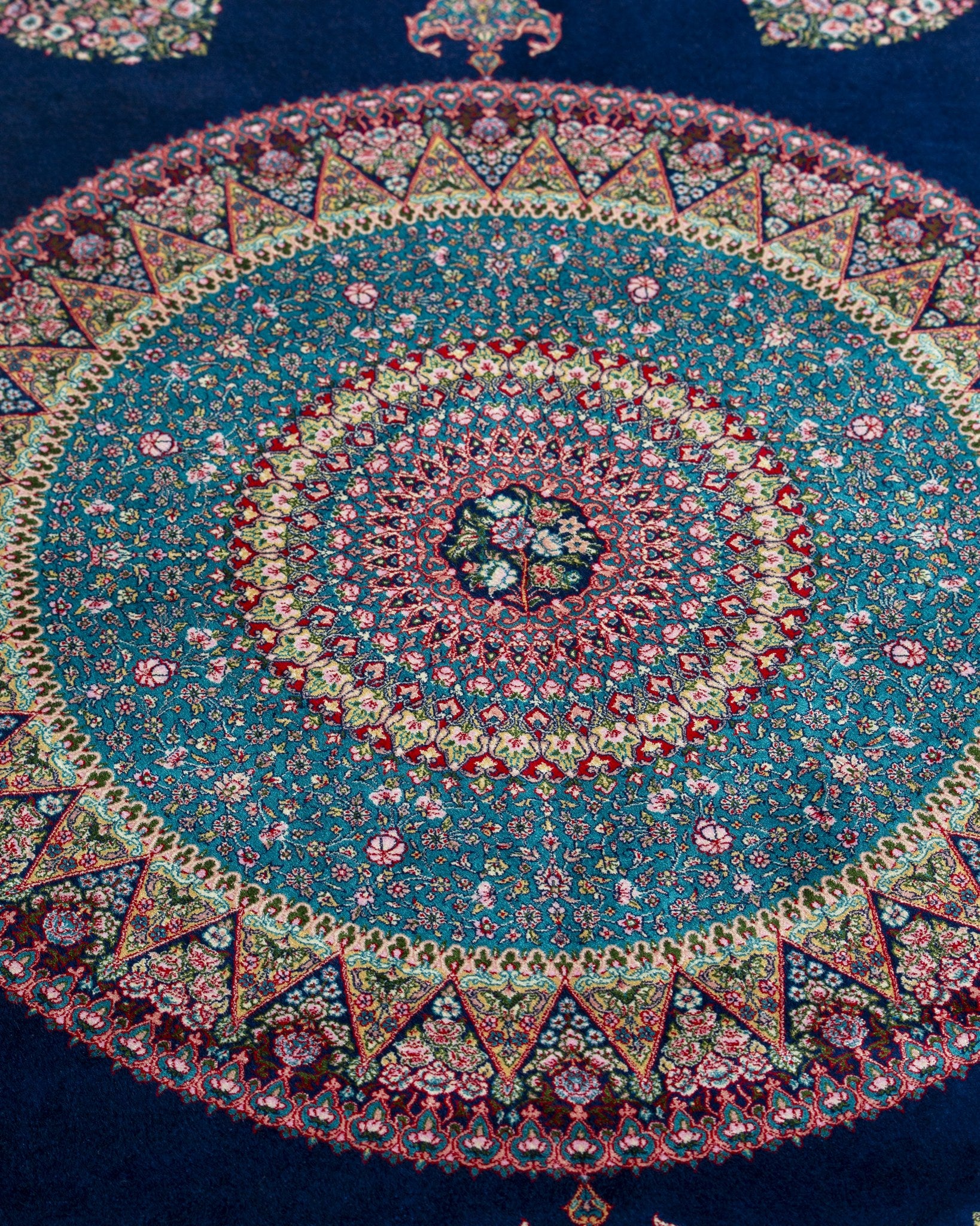 Close view of the Darya silk rug mandala in teal and rose on navy