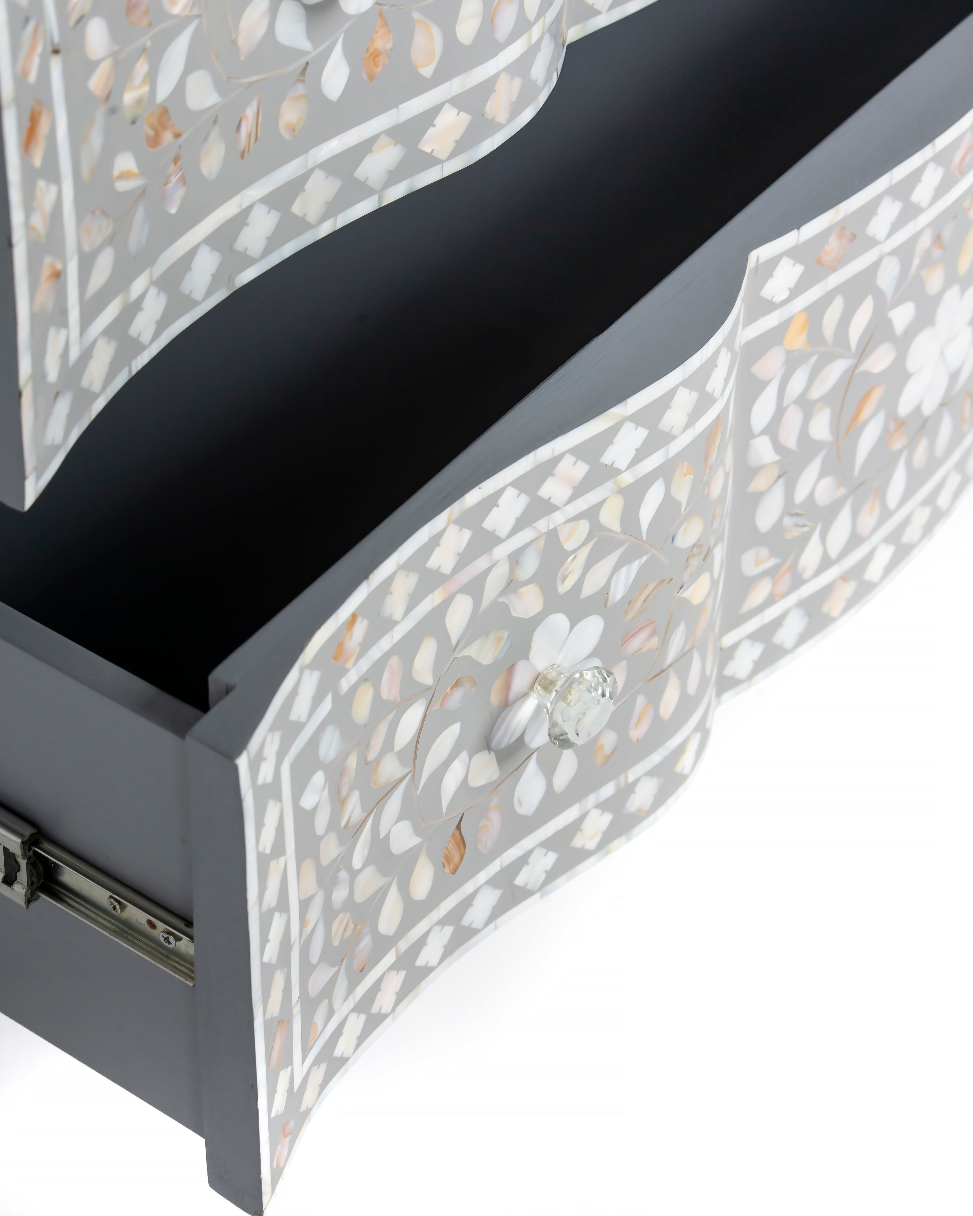 Crystal knob and floral inlay detail on open drawer of grey chest