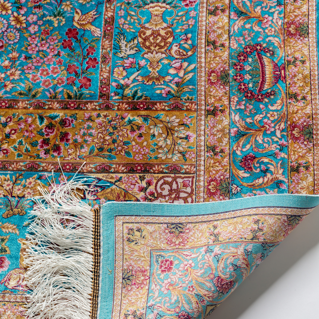 Neriah Silk Rug featuring ruby red floral and bird motifs on an aqua-blue base with golden ornate panels, size 150x100 cm.