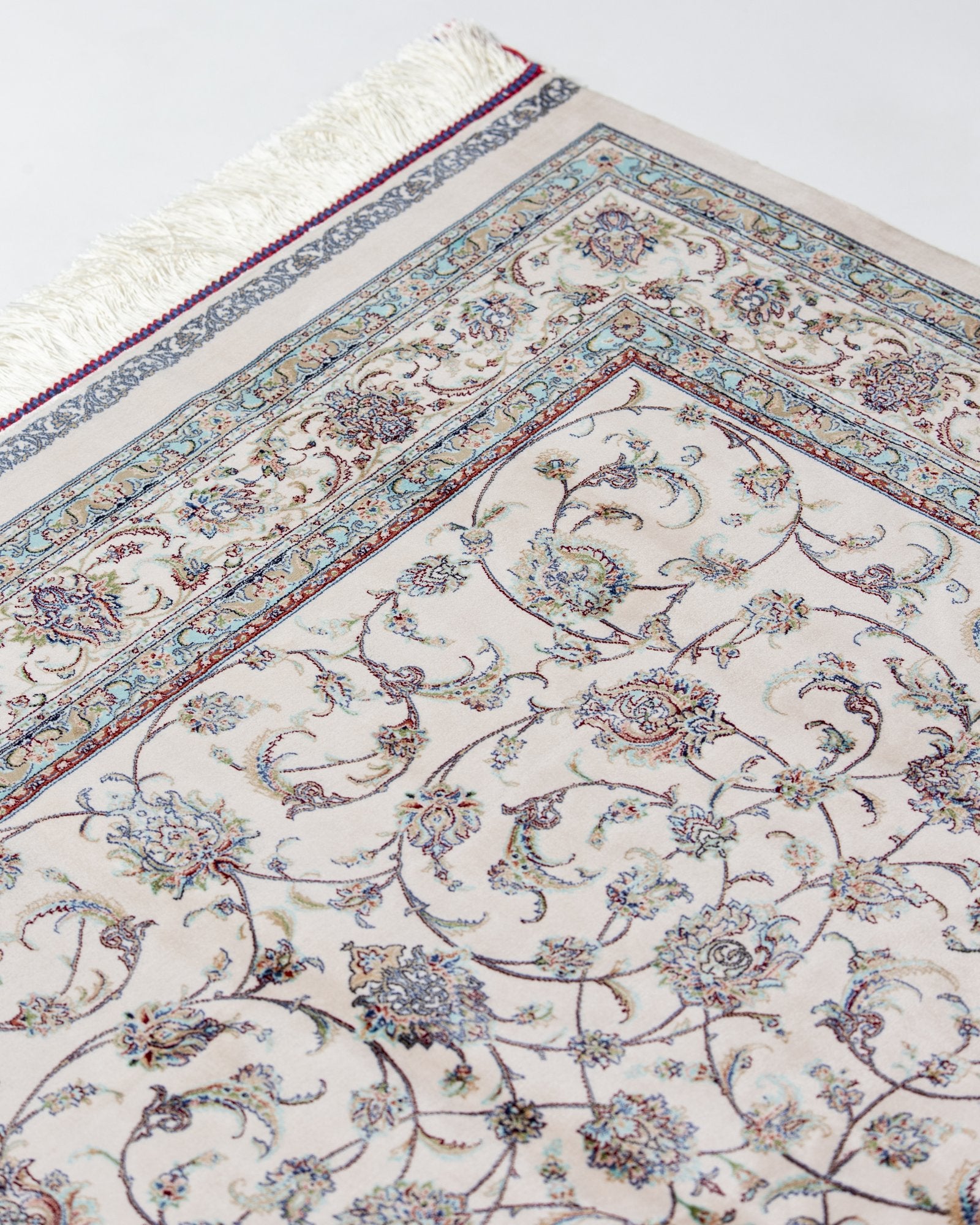 angled view with a fringed end on the Parisa ivory silk rug