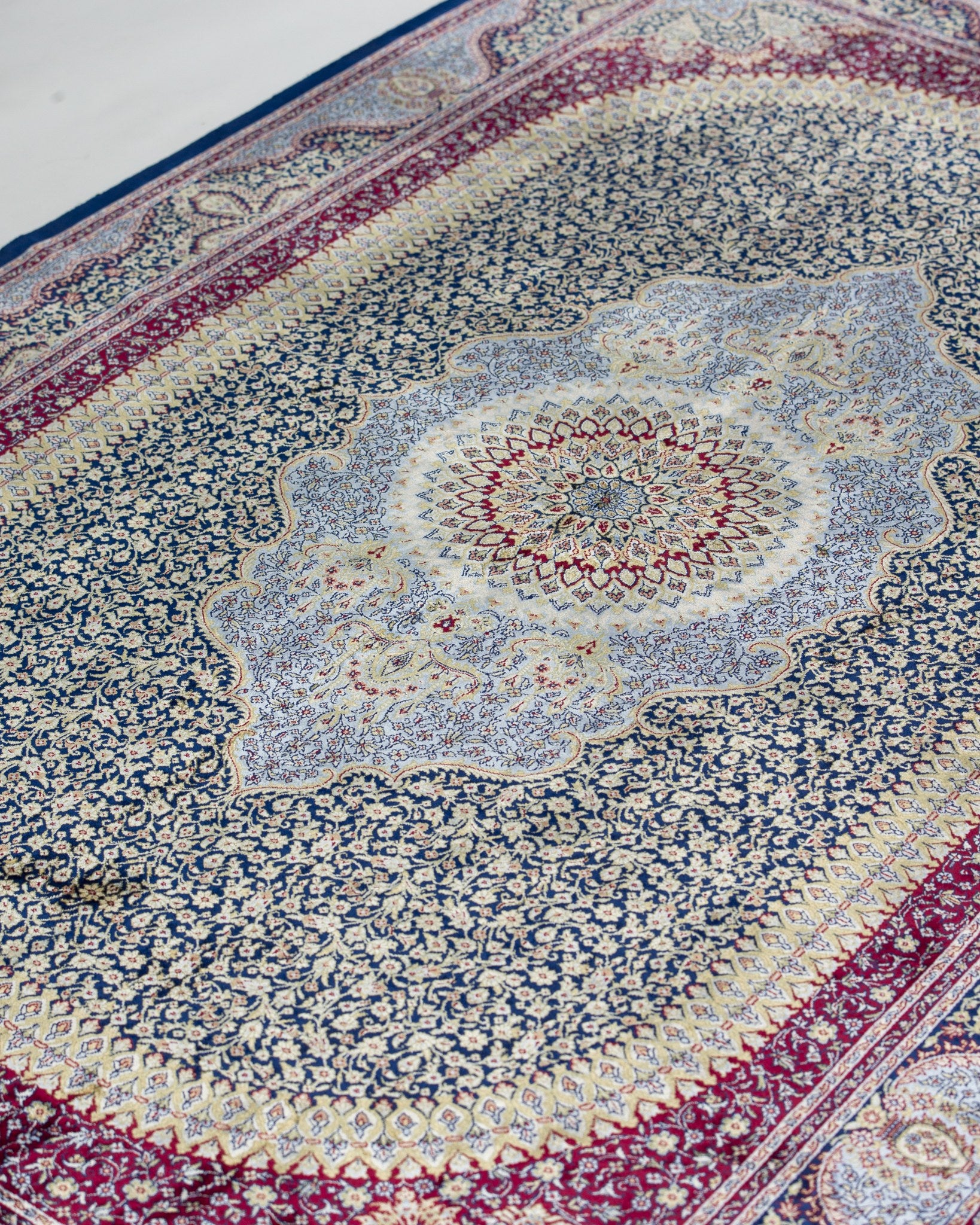 Close view of the Roya silk rug medallion in sage green and plum