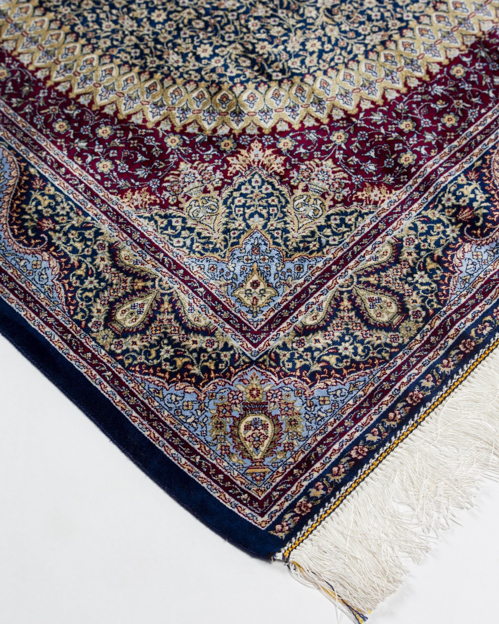 Plum border of the Roya green silk rug with silk fringe