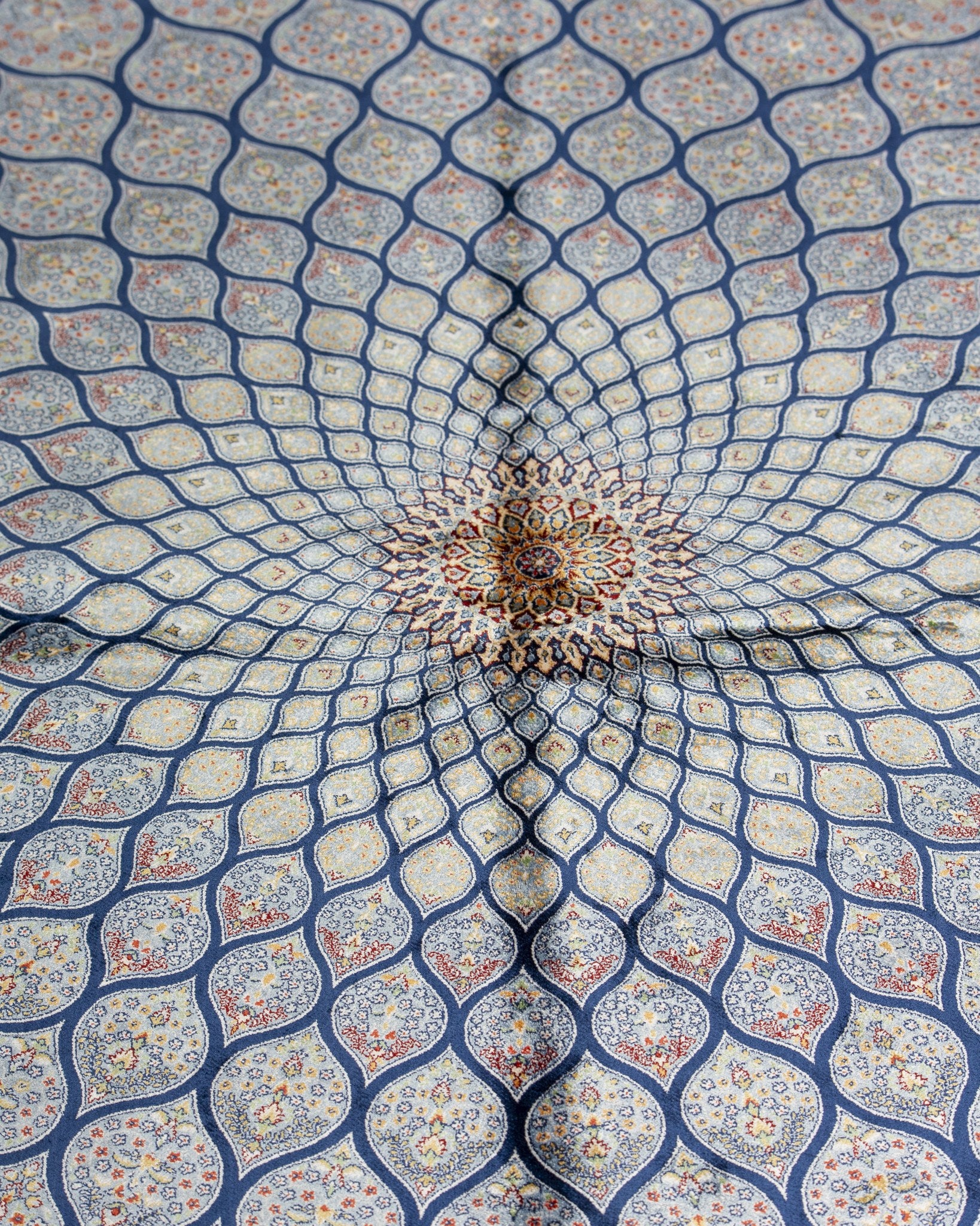 Close view of the Tavoos silk rug spiralling sunburst in blue and silver