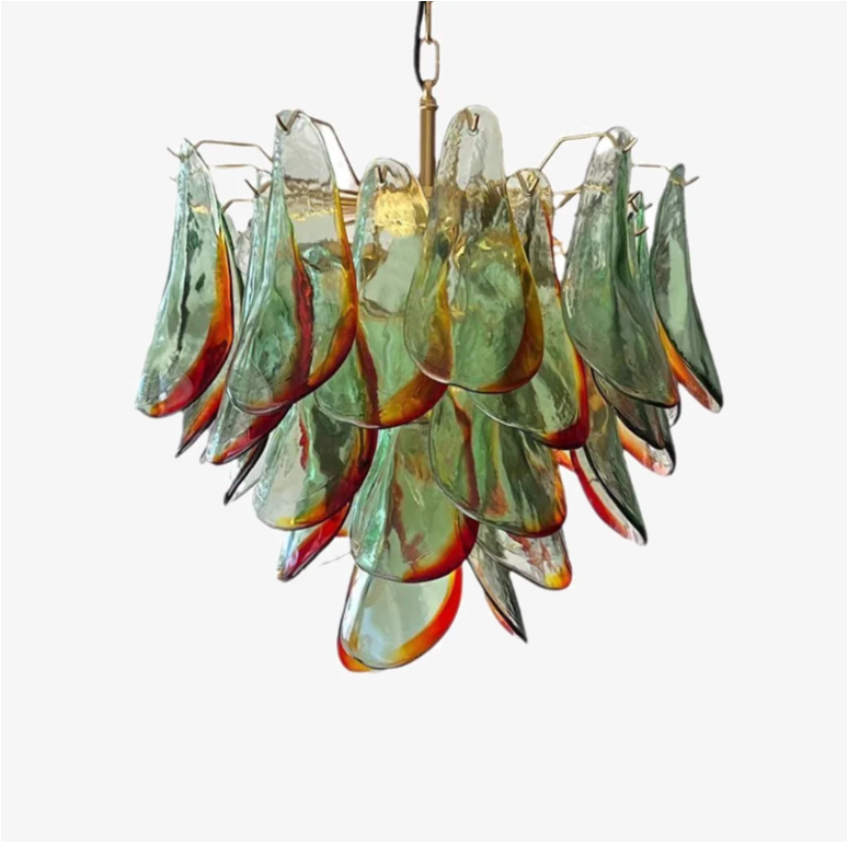 The Botanic Chandelier by The Qratist features handcrafted green and amber glass leaves layered around a refined metal frame, creating a sculptural botanical statement inspired by nature.