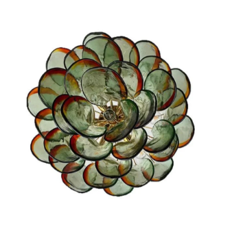 The Botanic Chandelier by The Qratist features handcrafted green and amber glass leaves layered around a refined metal frame, creating a sculptural botanical statement inspired by nature.