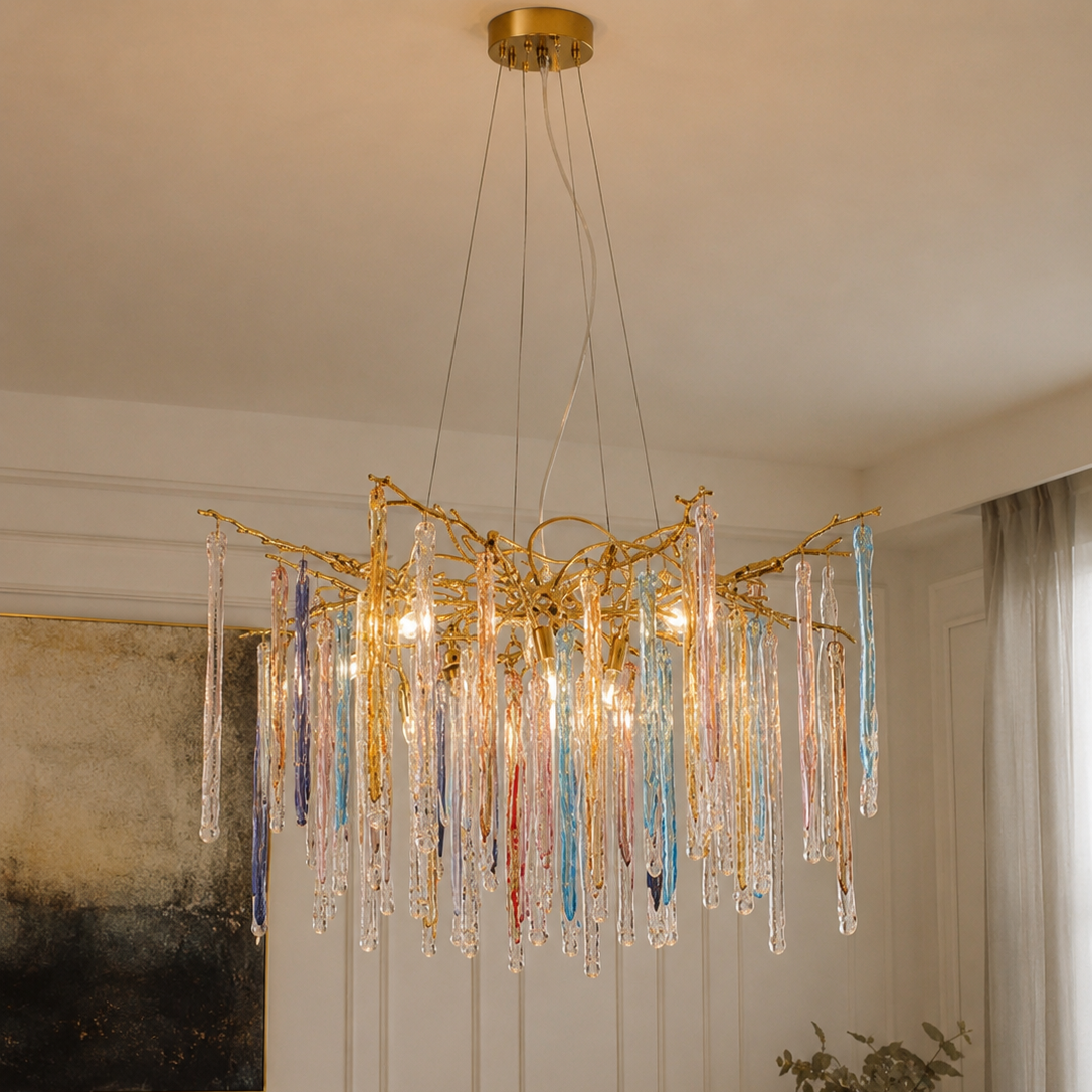 The Kryptonite Chandelier by The Qratist features handcrafted glass rods suspended from an organic brass framework, creating a bold sculptural statement inspired by crystalline formations.
