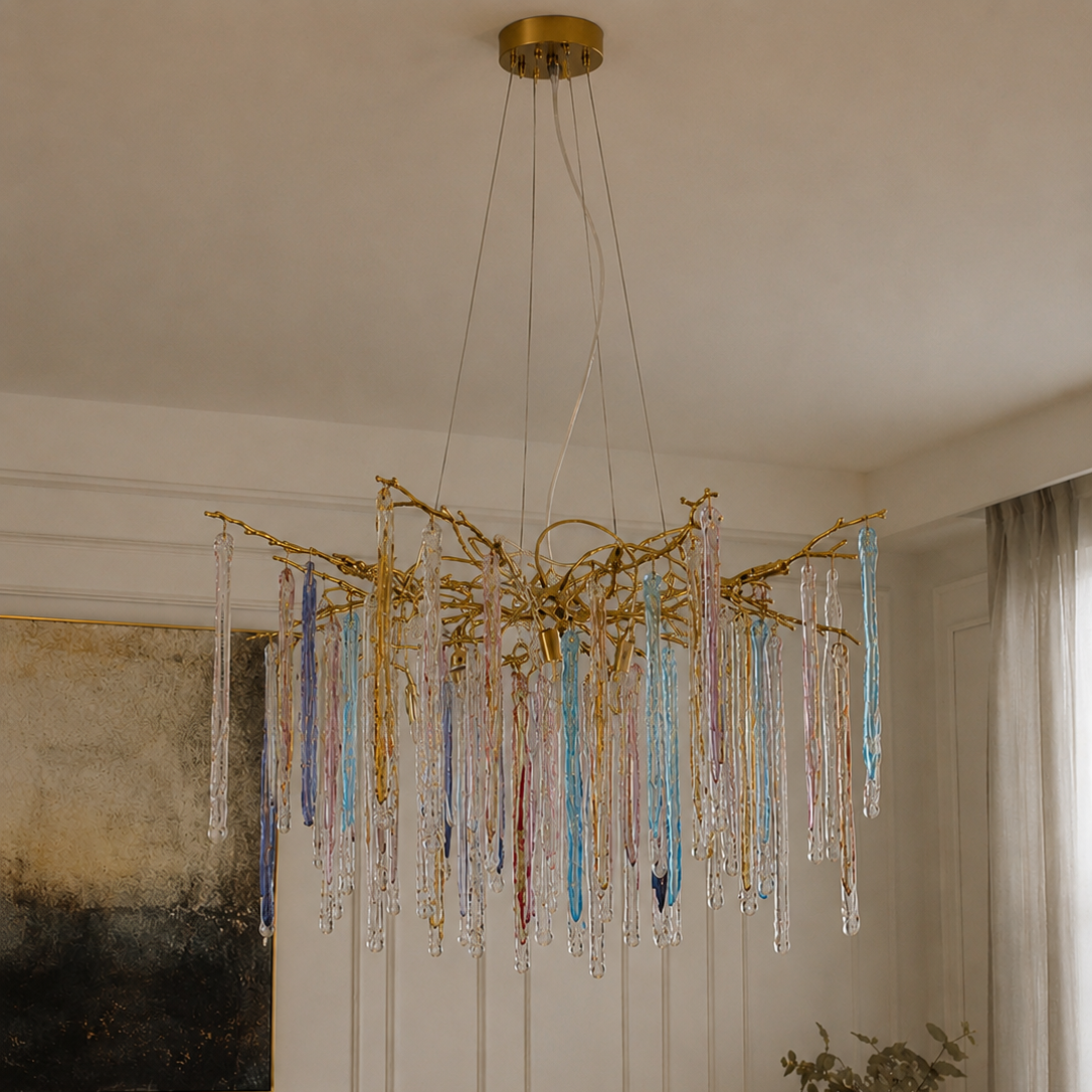 The Kryptonite Chandelier by The Qratist features handcrafted glass rods suspended from an organic brass framework, creating a bold sculptural statement inspired by crystalline formations.