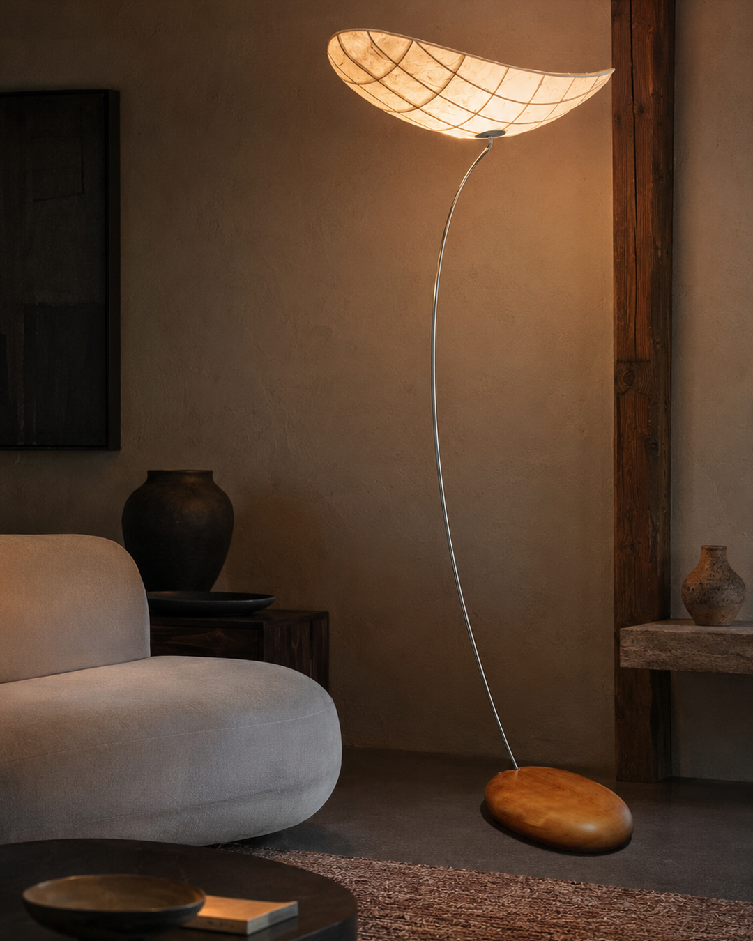 The Manta Floor Lamp by The Qratist features a handcrafted manta ray inspired fabric shade suspended on a slender metal frame with a natural wood base, creating warm ambient illumination.