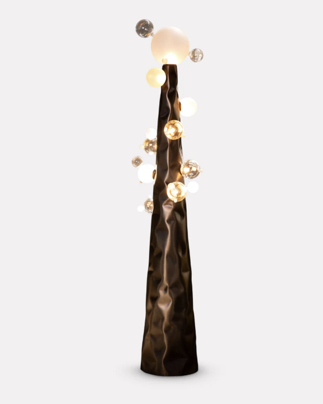 The Molecular Floor Lamp by The Qratist features a sculptural matte bronze steel column surrounded by handcrafted blown glass spheres, creating a striking molecular inspired floor lamp with warm ambient illumination.