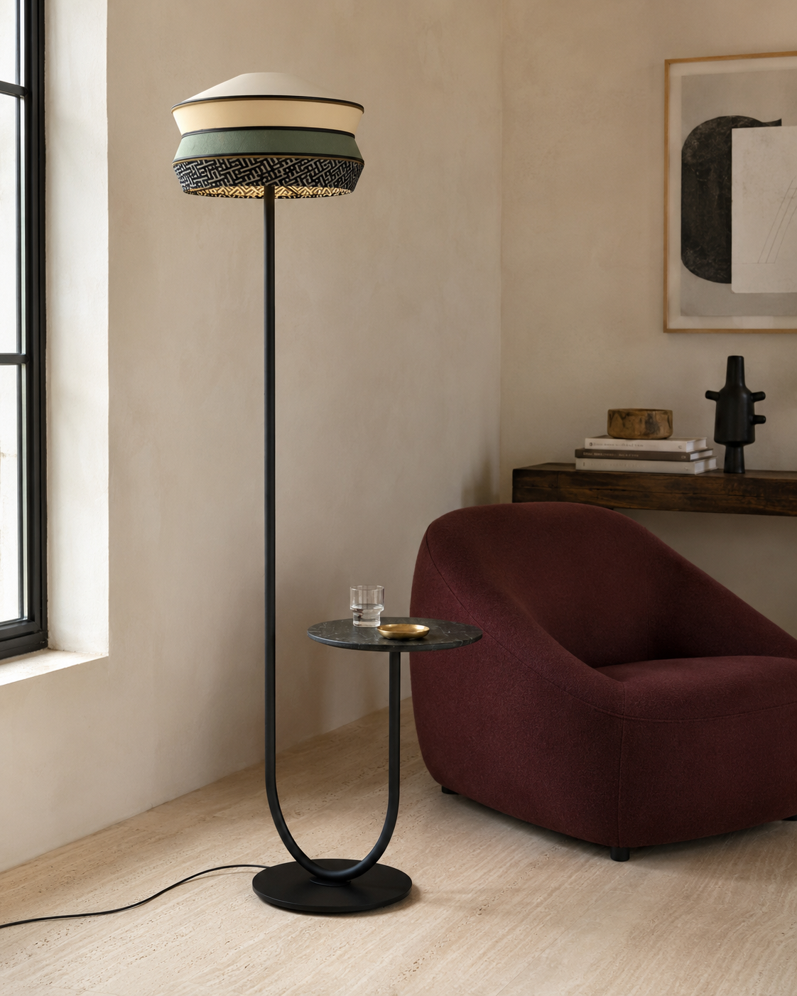 The Parasol Floor Lamp by The Qratist features a layered fabric shade suspended on a sculptural black stainless steel frame with an integrated circular side table, creating an elegant multifunctional lighting statement.