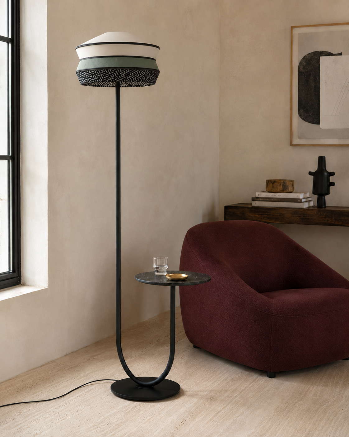 The Parasol Floor Lamp by The Qratist features a layered fabric shade suspended on a sculptural black stainless steel frame with an integrated circular side table, creating an elegant multifunctional lighting statement.