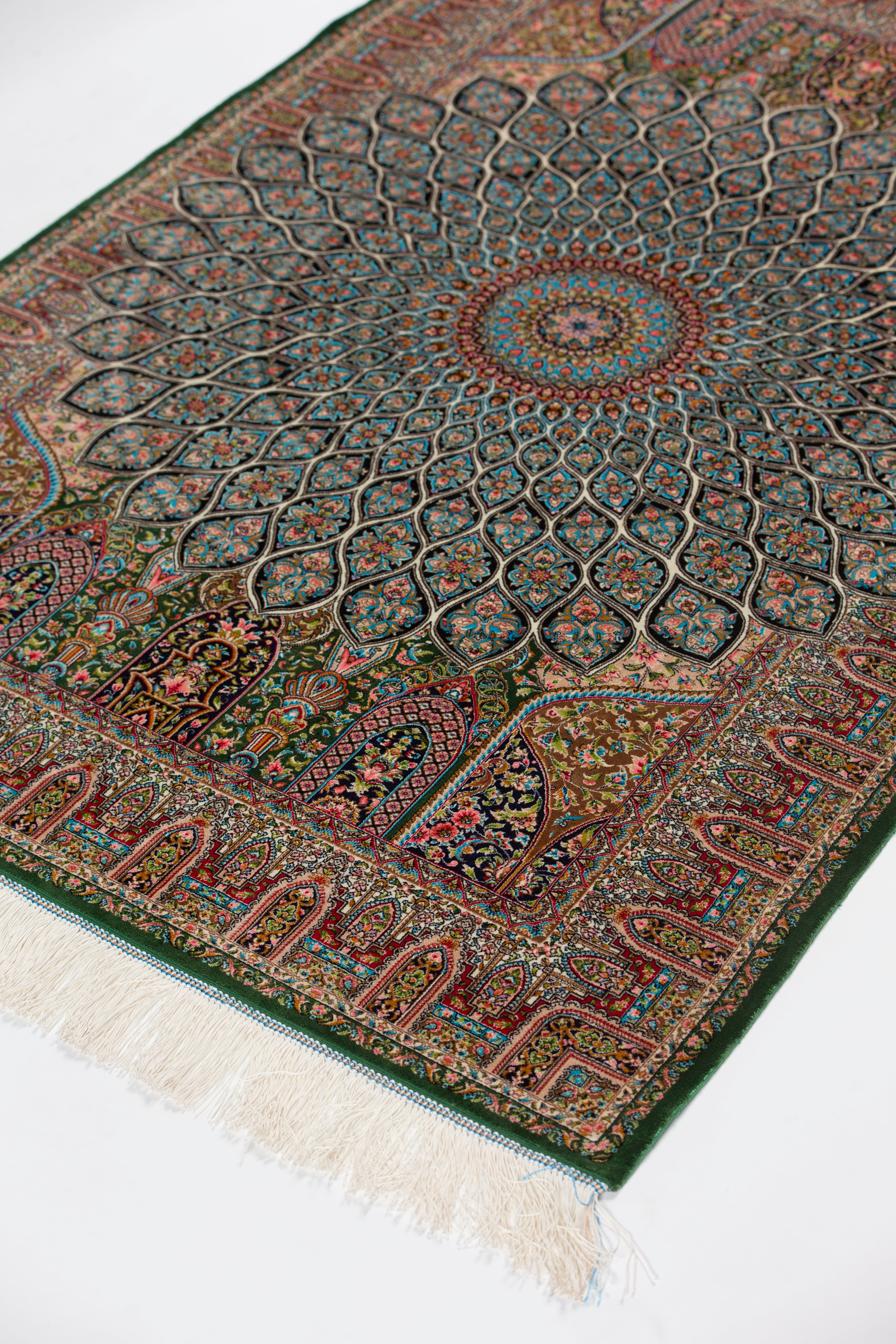 Angled view of the Zumurrud green silk rug with fringe